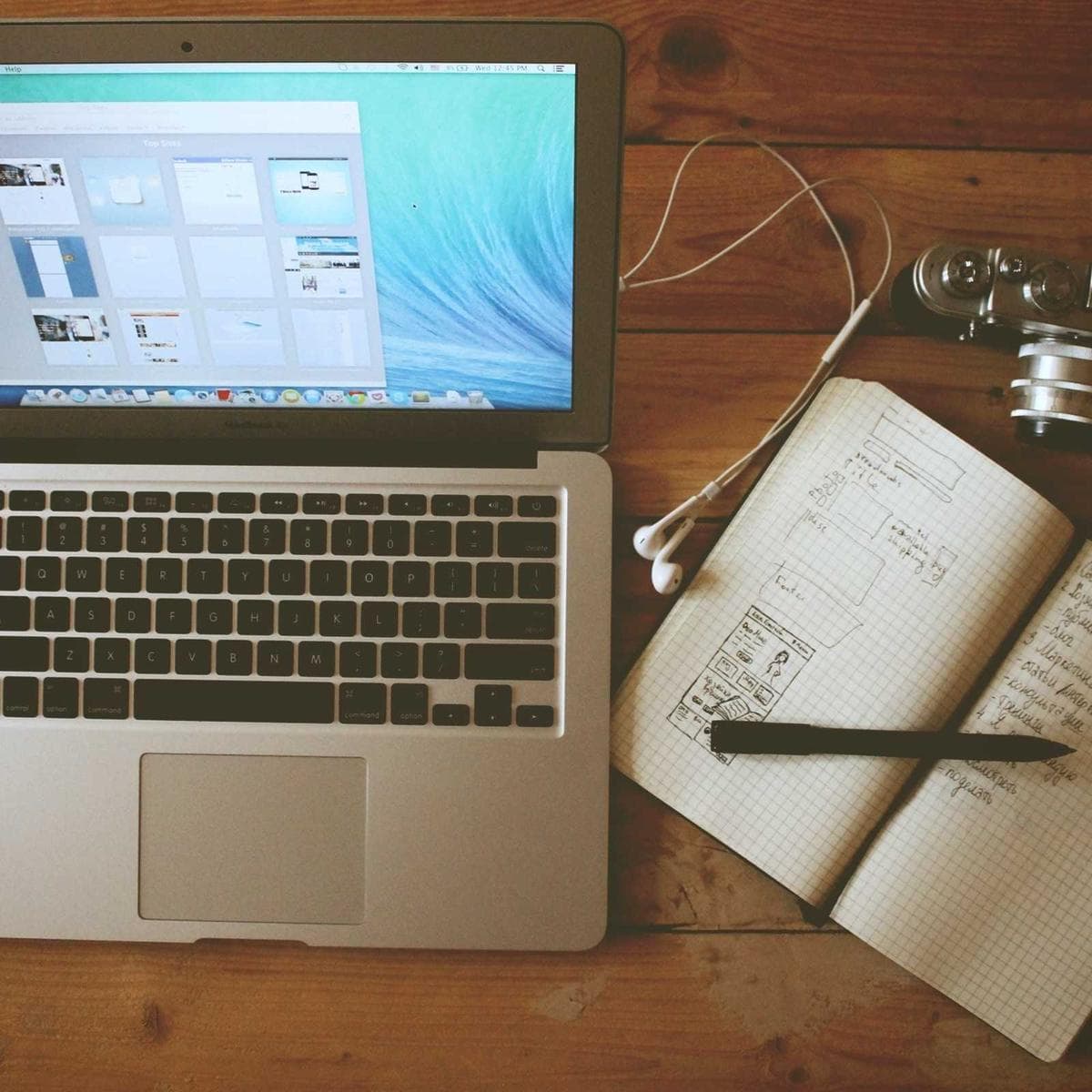 A laptop beside a notebook of rough sketches